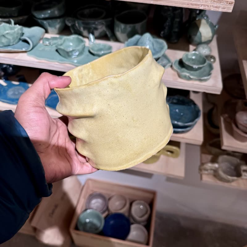 A hand holding an unfired clay cup